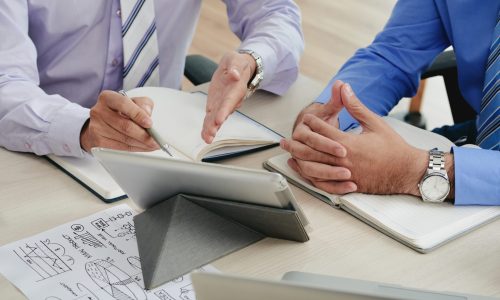 Close-up image of coworkers discussing data on tablet computer screen